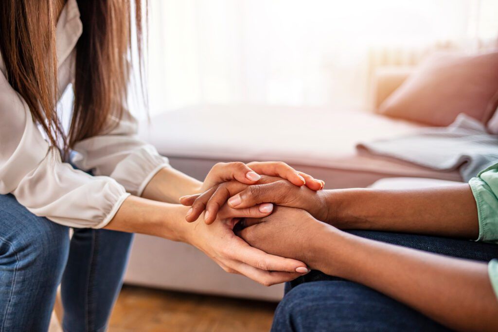 a woman is holding another woman 's hand while sitting on a couch .
