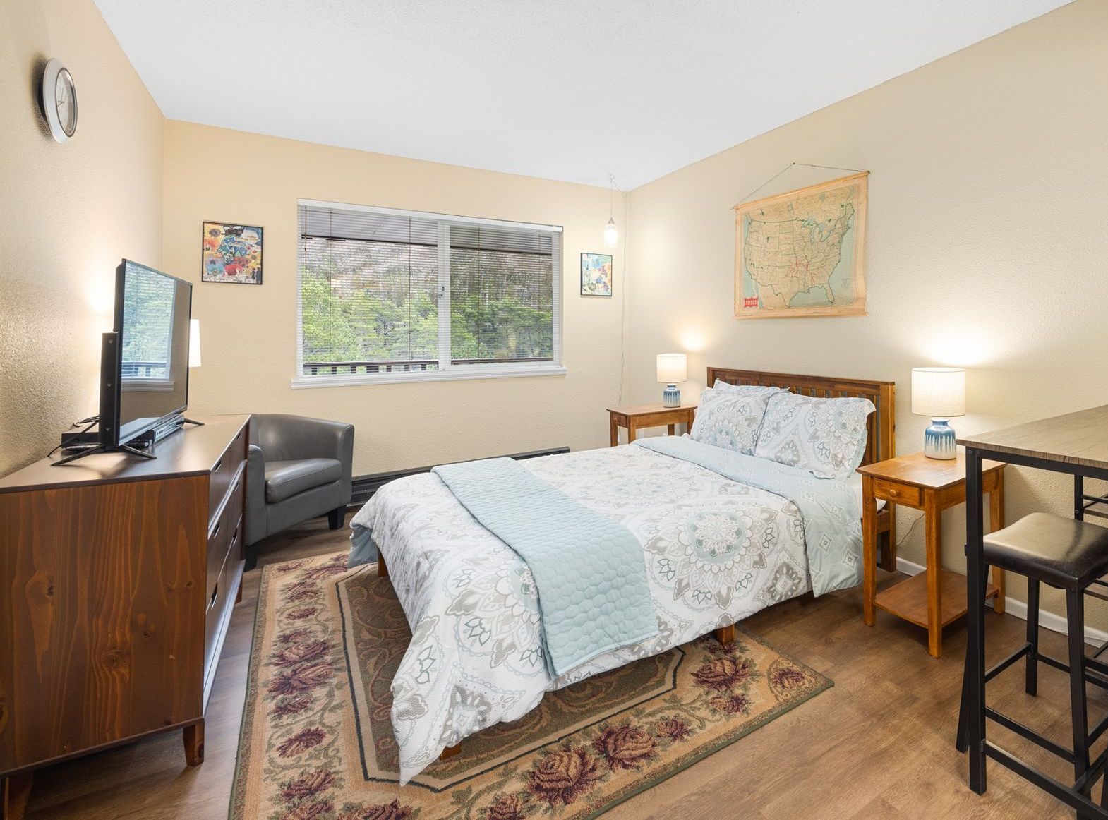 A bedroom with occasional chair and tv