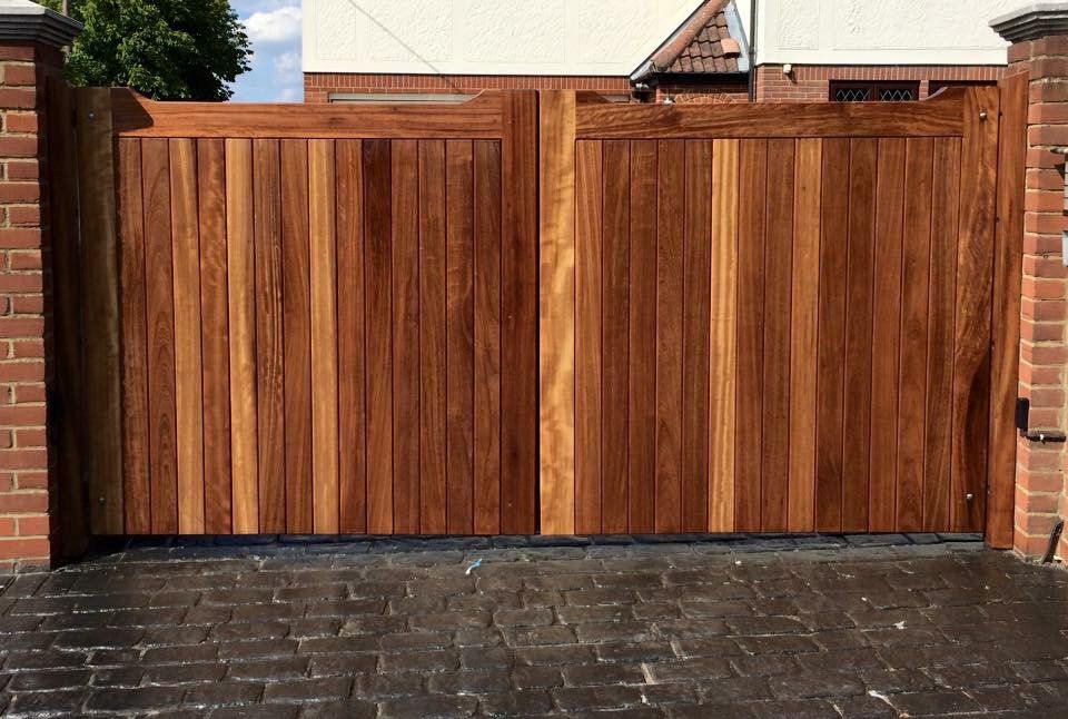 A wooden gate is sitting in front of a brick wall.