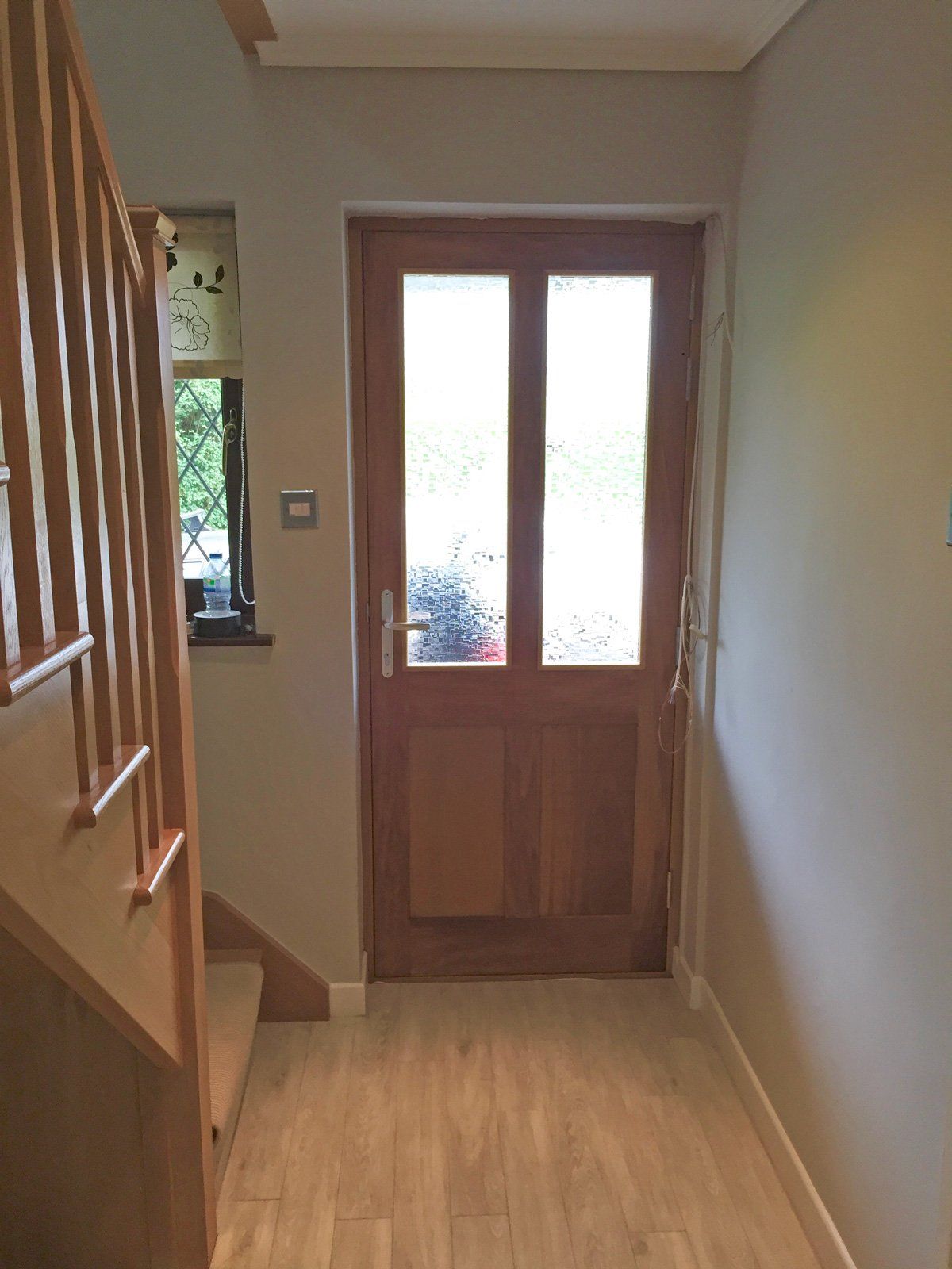 A hallway with a wooden door and stairs leading up to it.