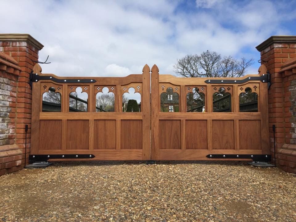 A wooden gate is sitting on top of a gravel driveway next to a brick wall.