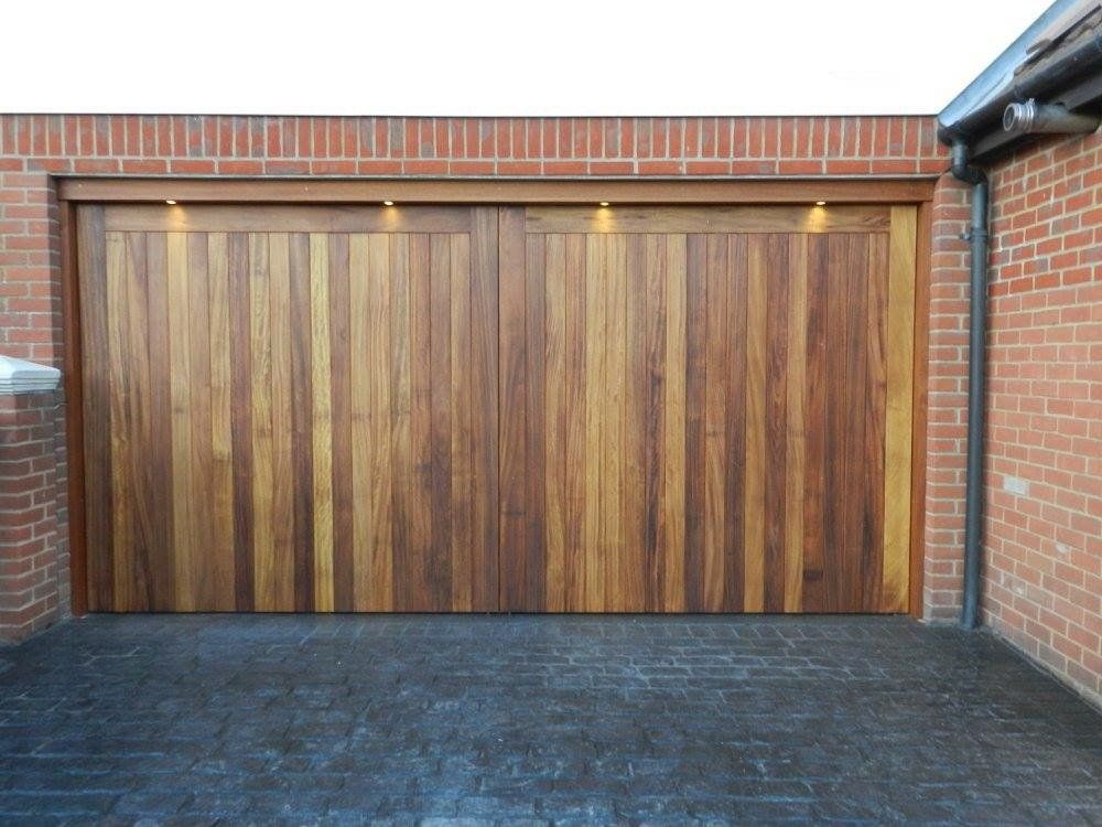 A wooden garage door is sitting next to a brick wall.