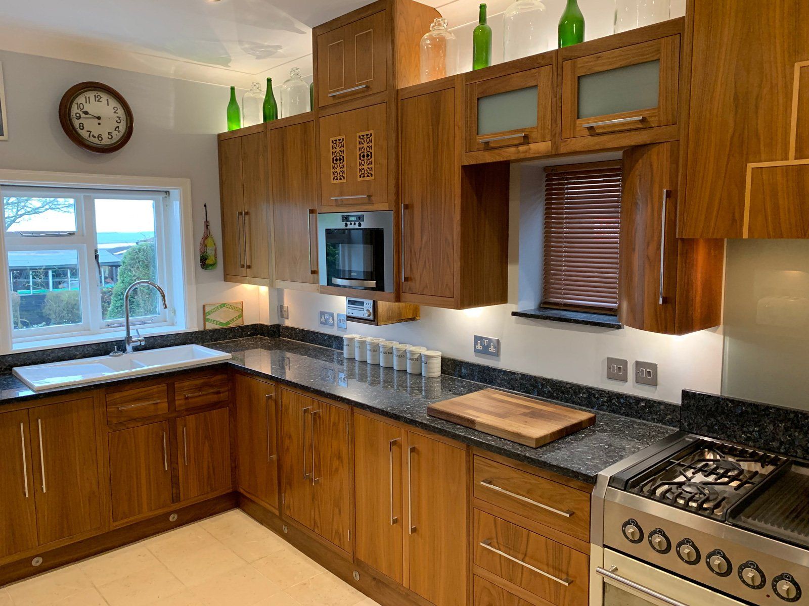 A kitchen with wooden cabinets , granite counter tops , stainless steel appliances and a clock on the wall.