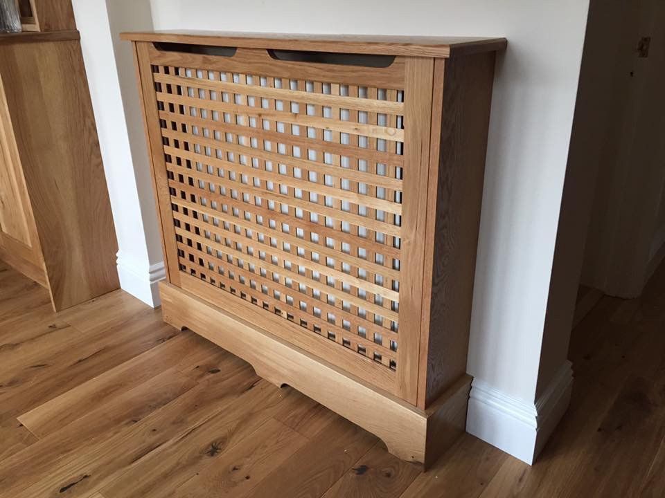 A wooden radiator cover is sitting on a wooden floor in a room.