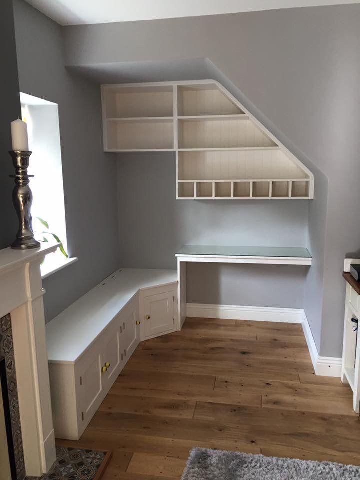 A living room with a desk , shelves and a fireplace.