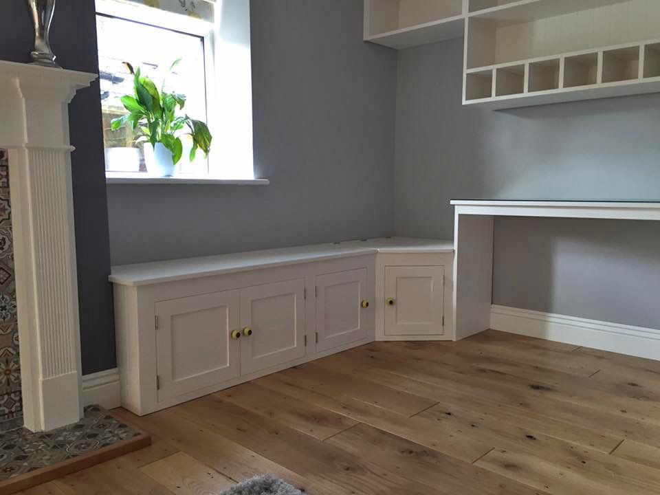 A living room with hardwood floors , a fireplace and a desk.