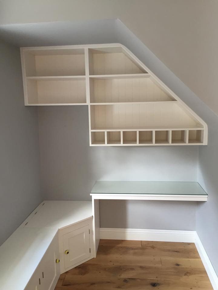 A corner of a room with a desk and shelves.