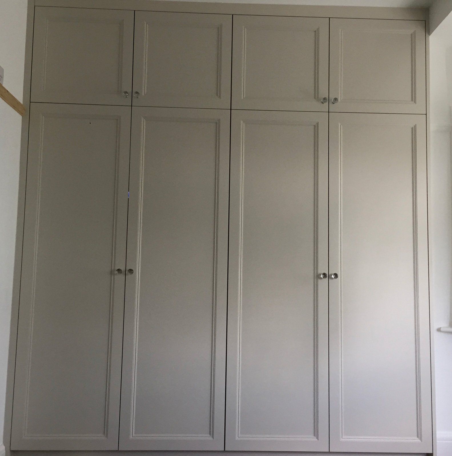 A closet with a lot of doors and drawers in a room.