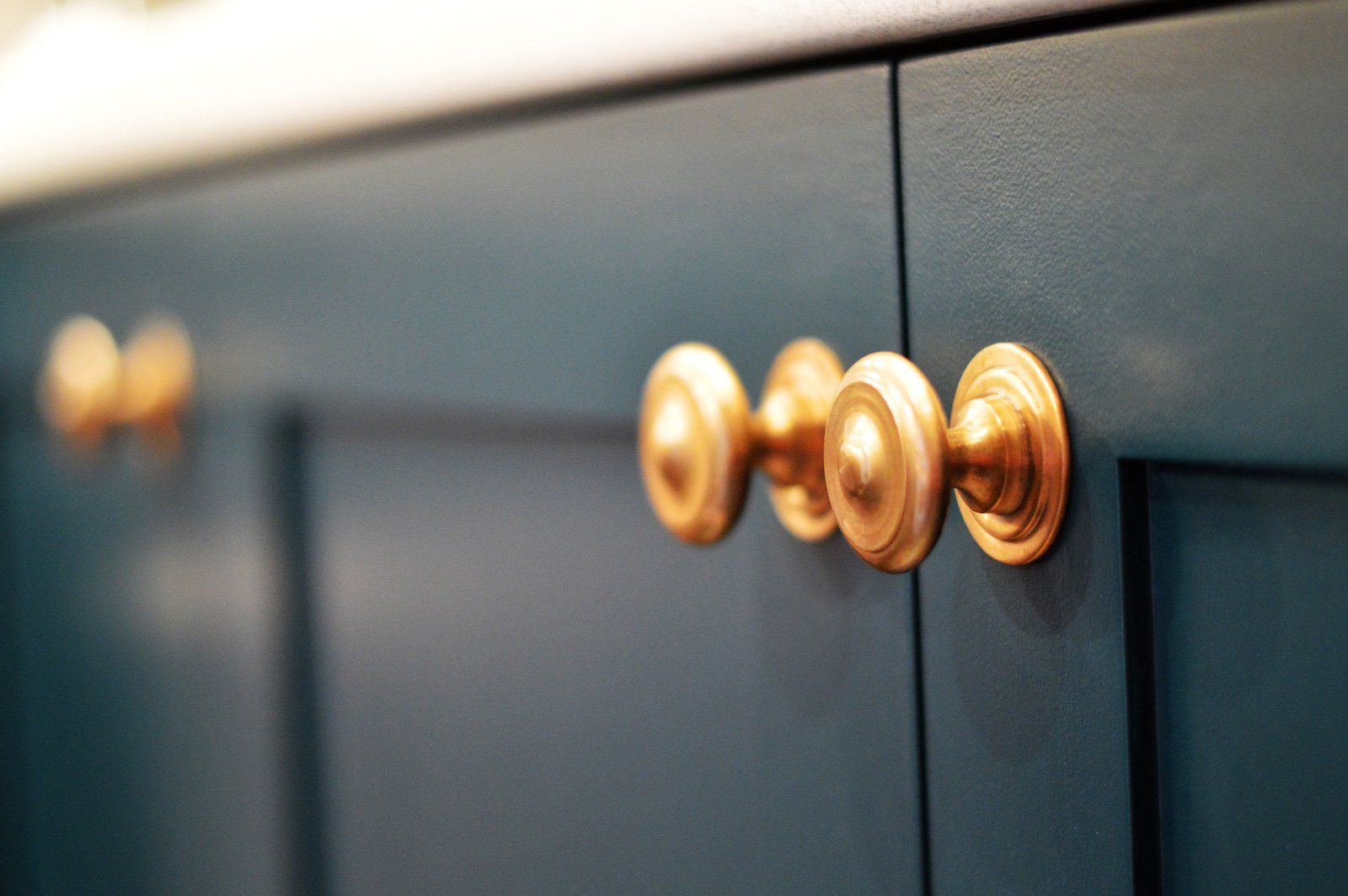 A close up of a blue cabinet with gold handles.