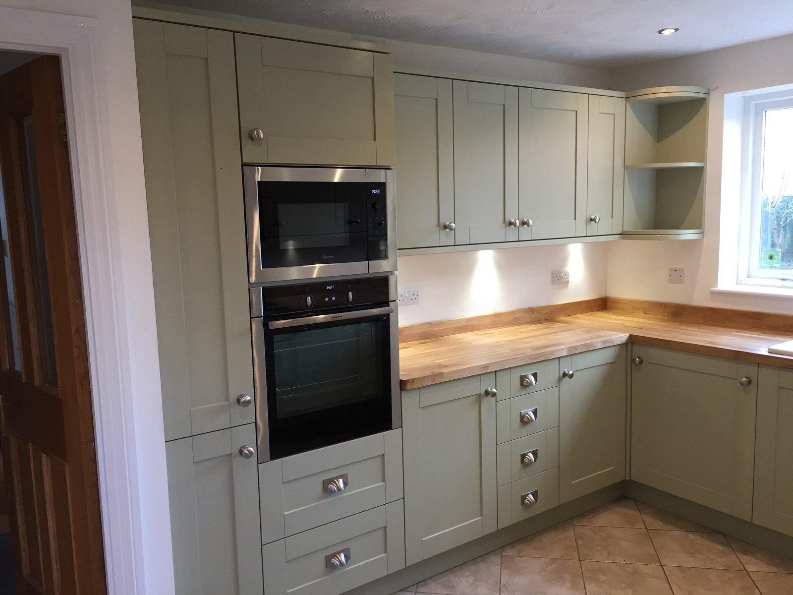 A kitchen with green cabinets and a stainless steel oven