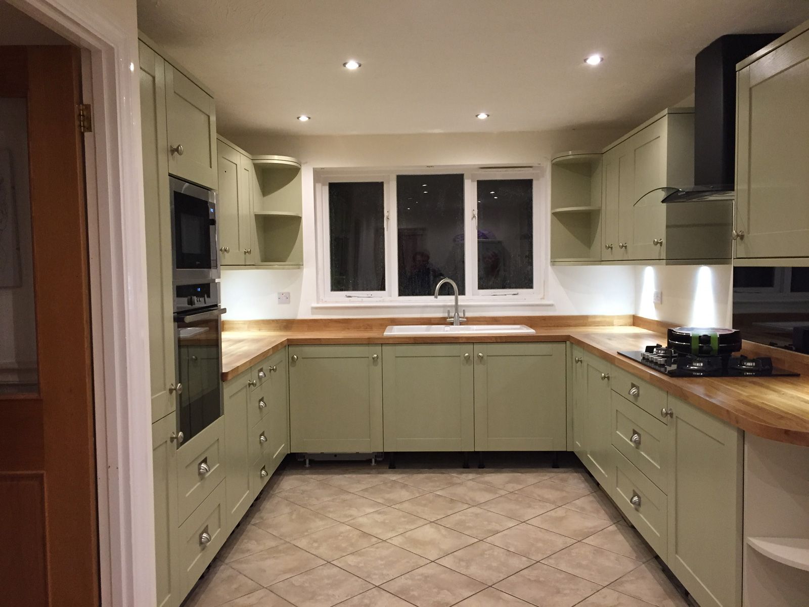 A kitchen with green cabinets and wooden counter tops