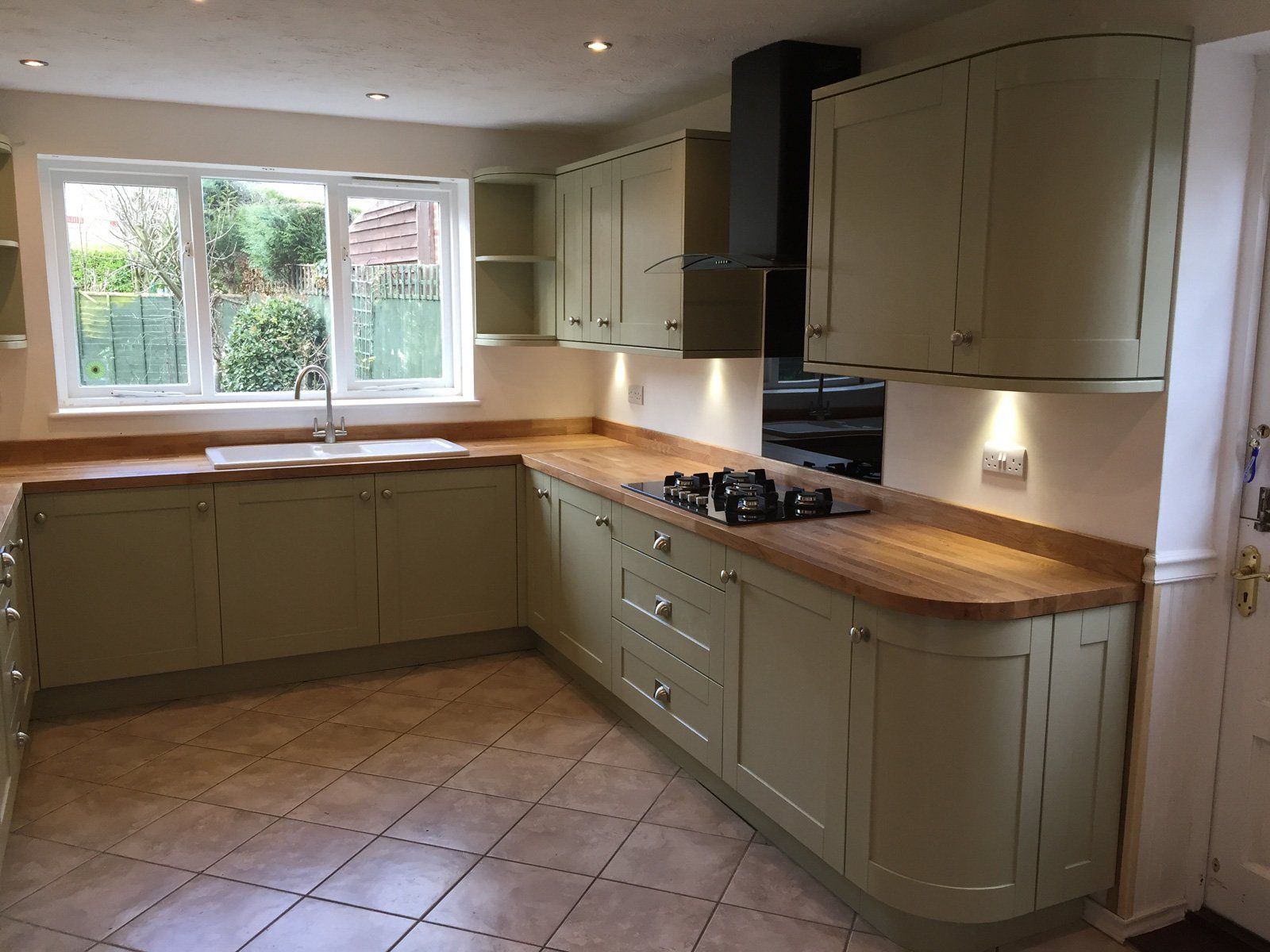 A kitchen with green cabinets and wooden counter tops