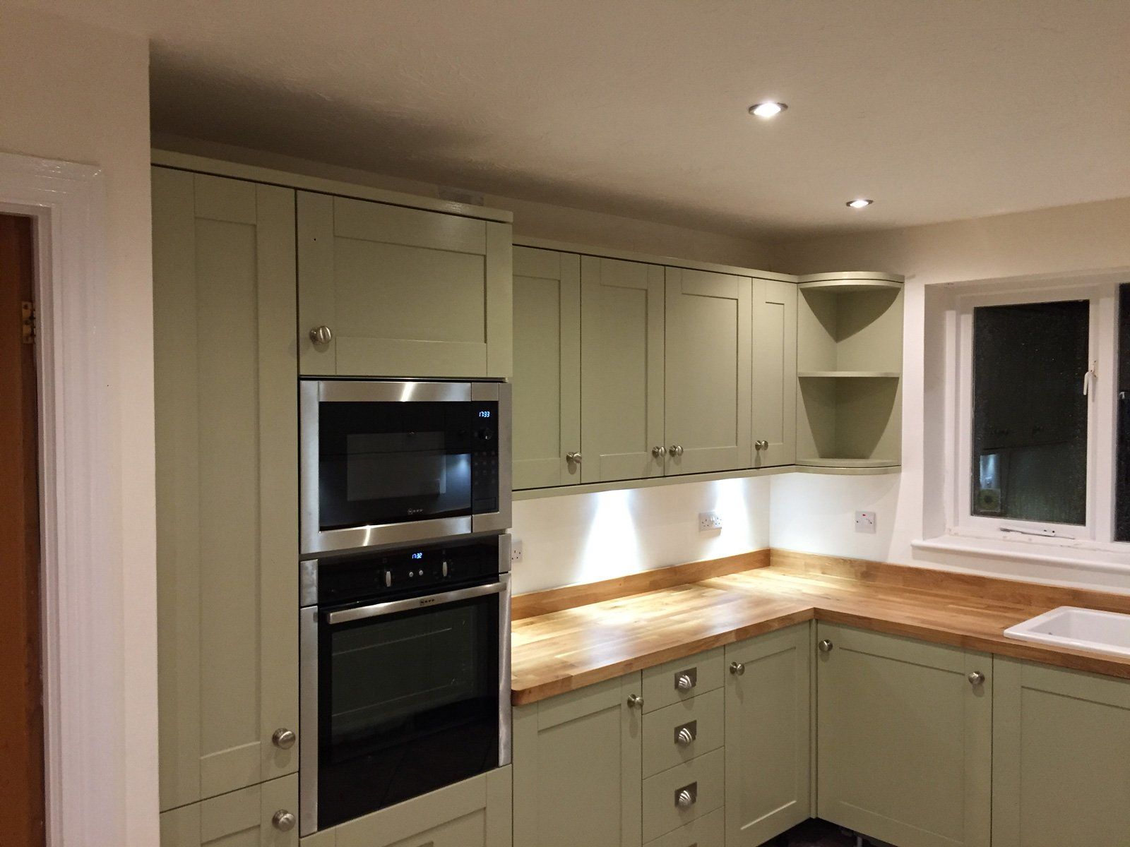 A kitchen with green cabinets and a stainless steel oven.