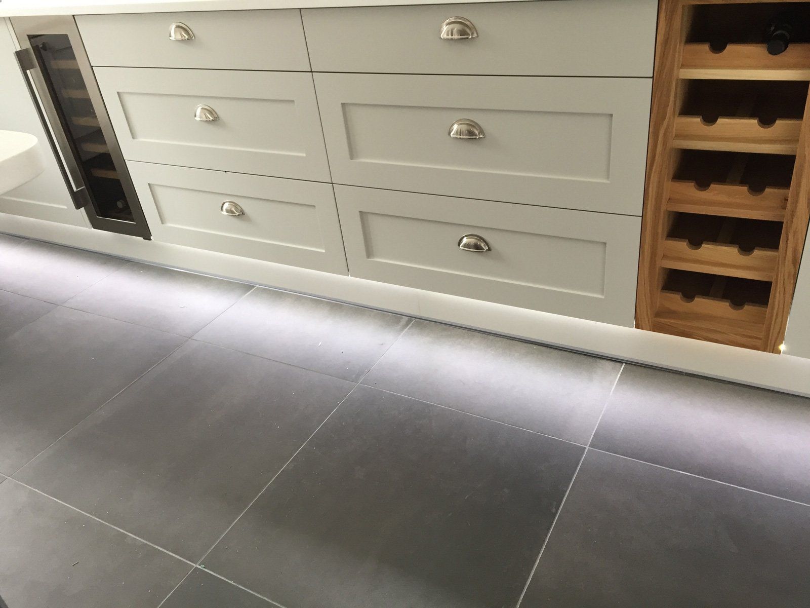 A kitchen with white cabinets and a wine cooler