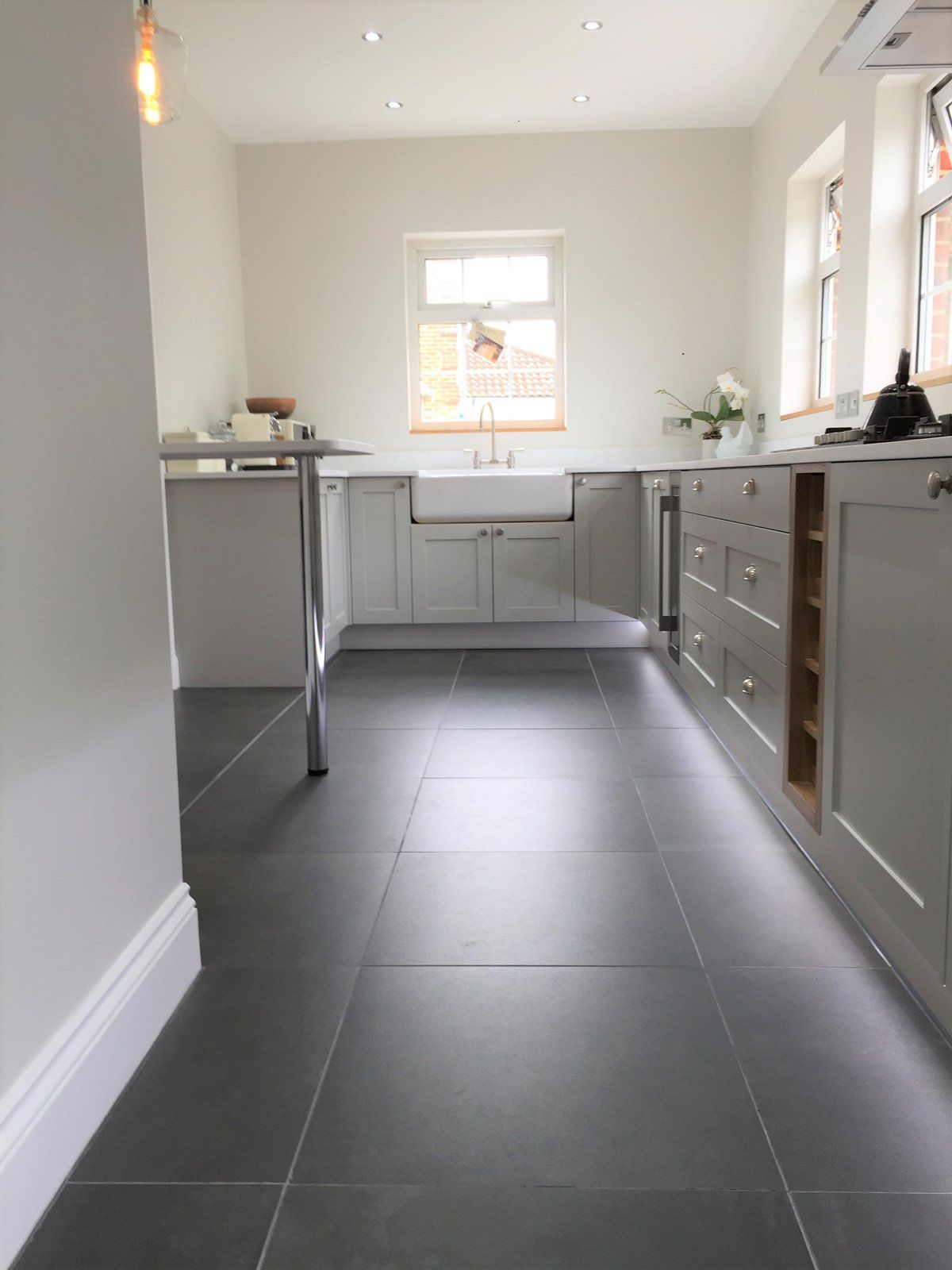 A kitchen with white cabinets and black tile floors