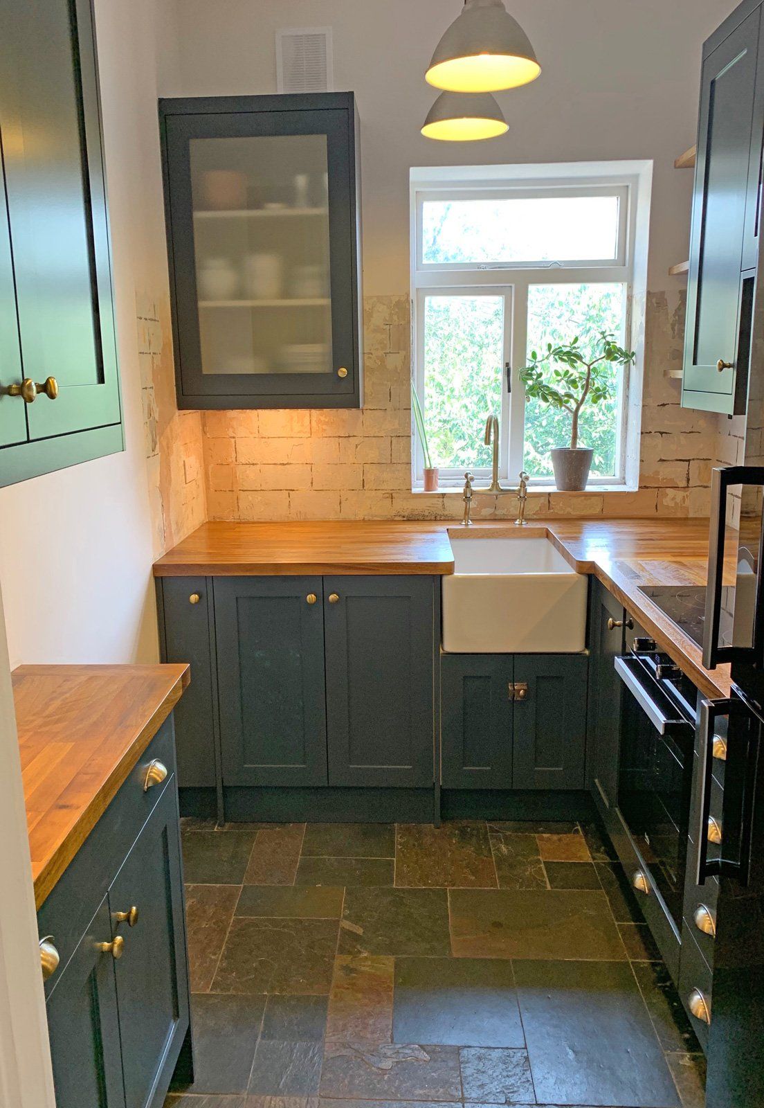 A kitchen with a sink , stove , cabinets and a window