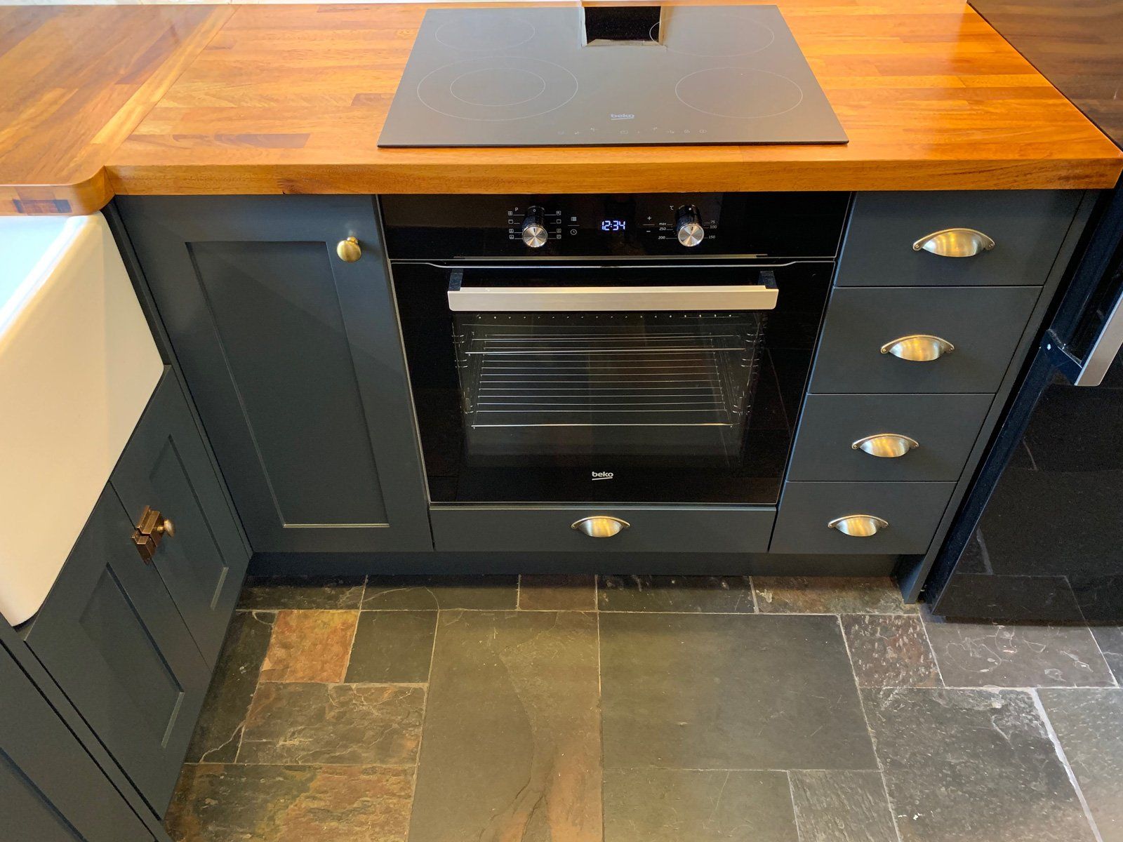 A black oven is sitting under a wooden counter top in a kitchen.