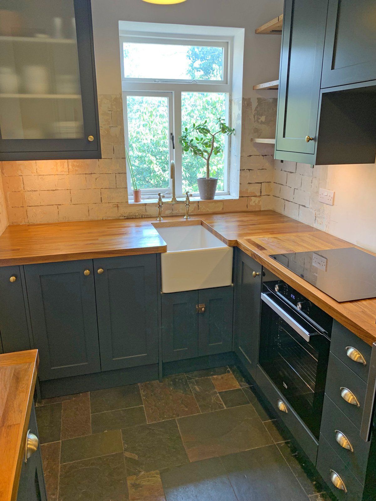 A kitchen with a sink , stove , cabinets and a window.