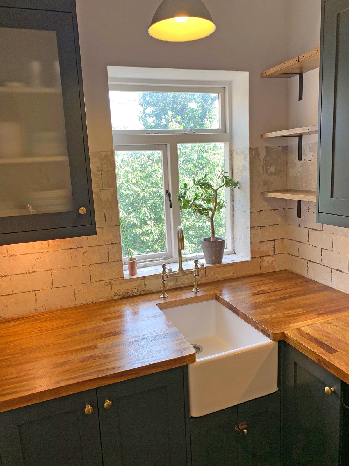 A kitchen with a sink , cabinets , and a window.