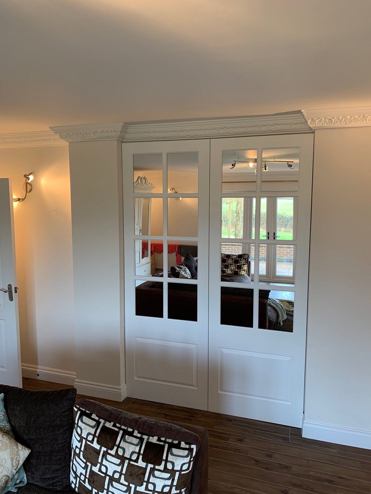 A living room with a couch and a mirrored door.