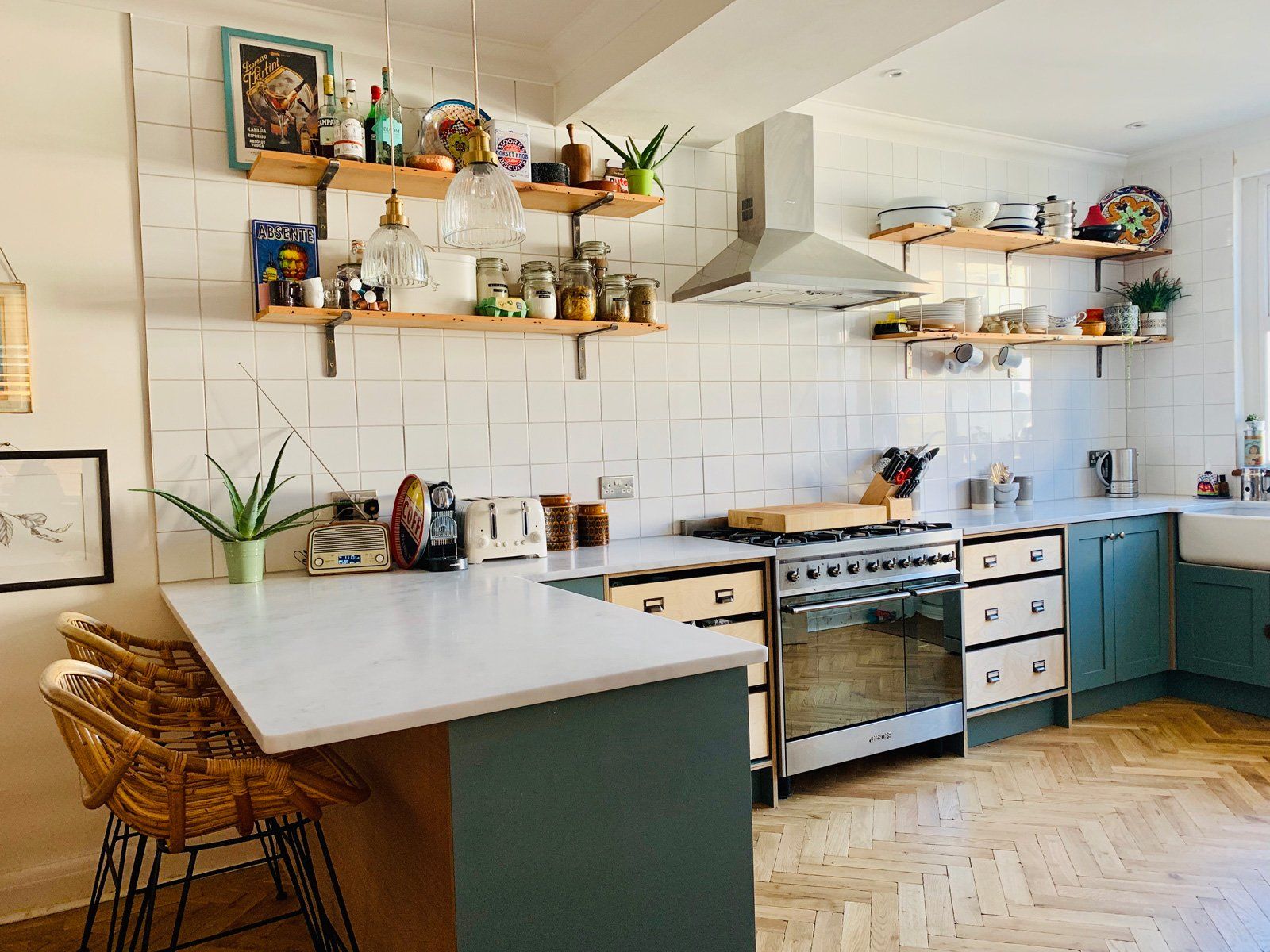 A kitchen with a stove , sink , cabinets and shelves.