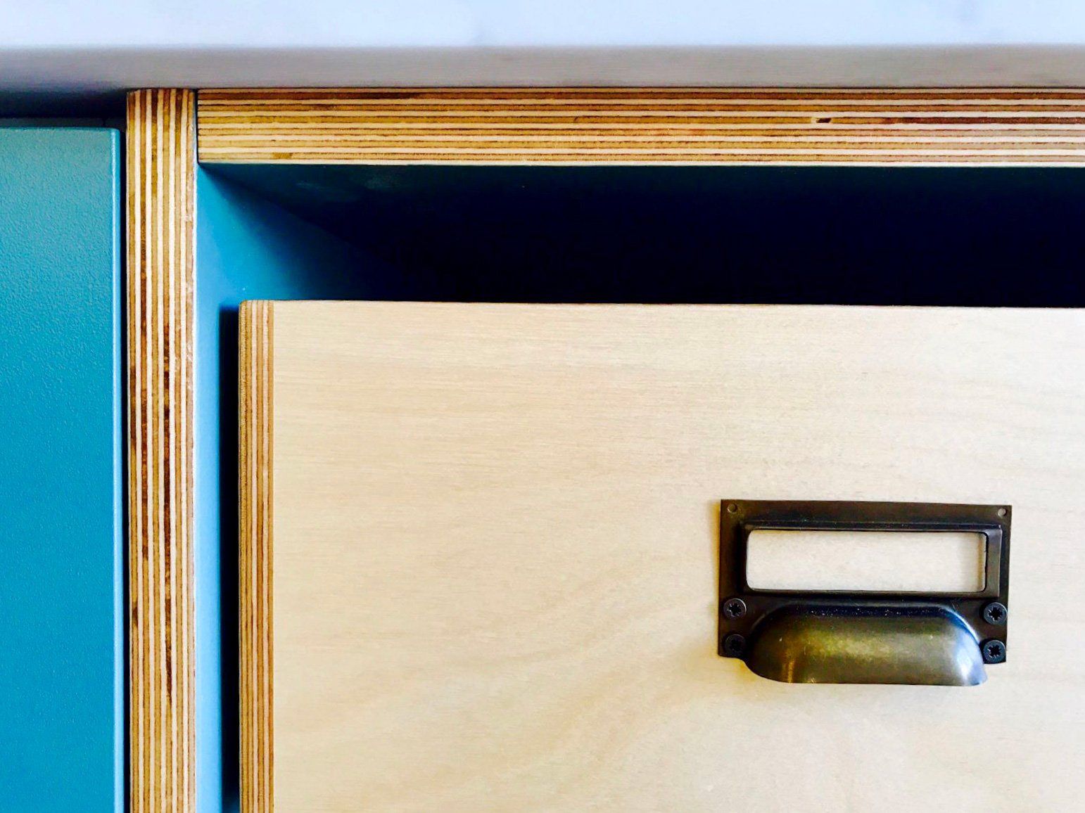 A close up of a wooden drawer with a brass handle.