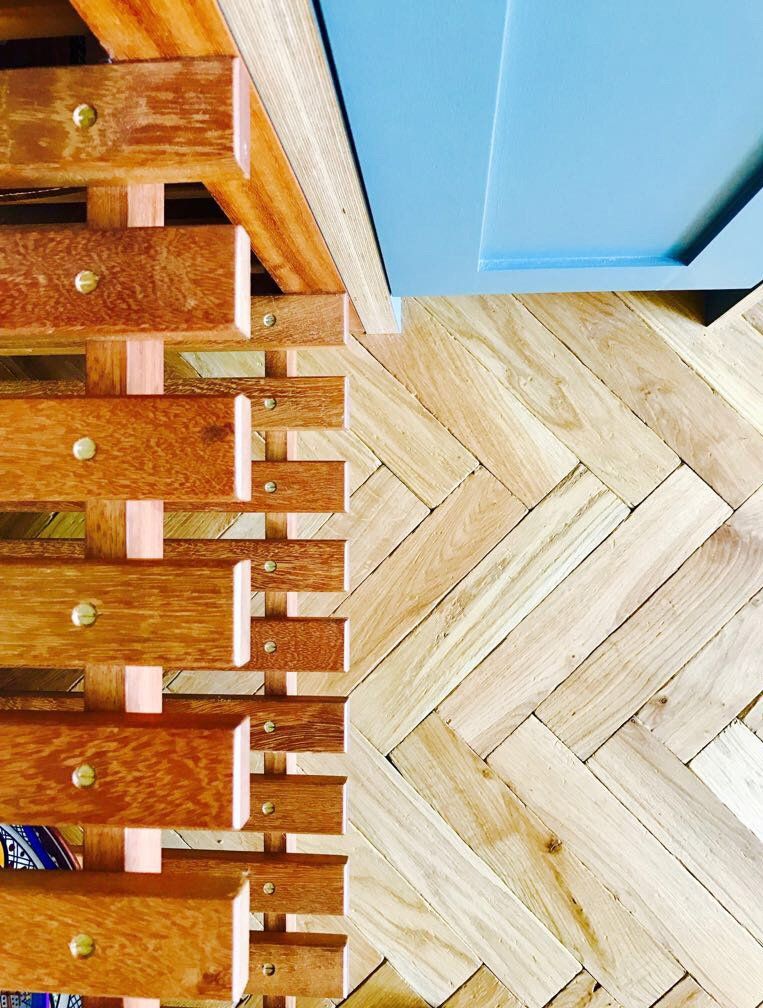 A close up of a wooden shelf on a herringbone floor