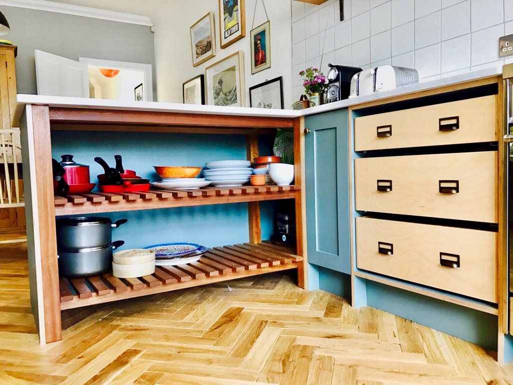 A kitchen with a wooden shelf filled with pots and pans.