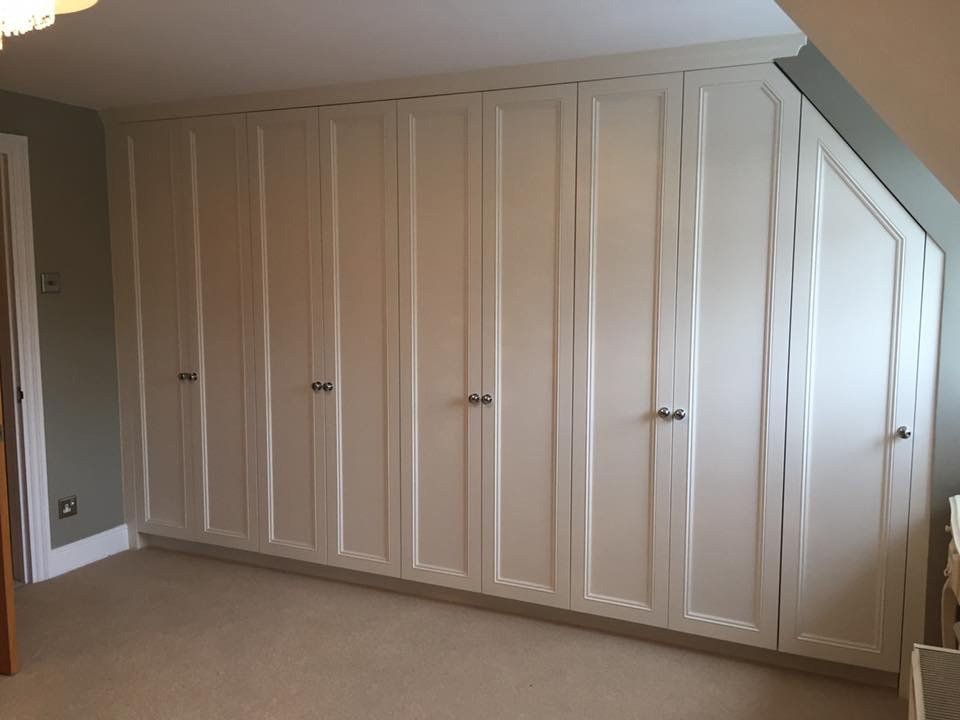 A room with a lot of white cabinets and a slanted ceiling.