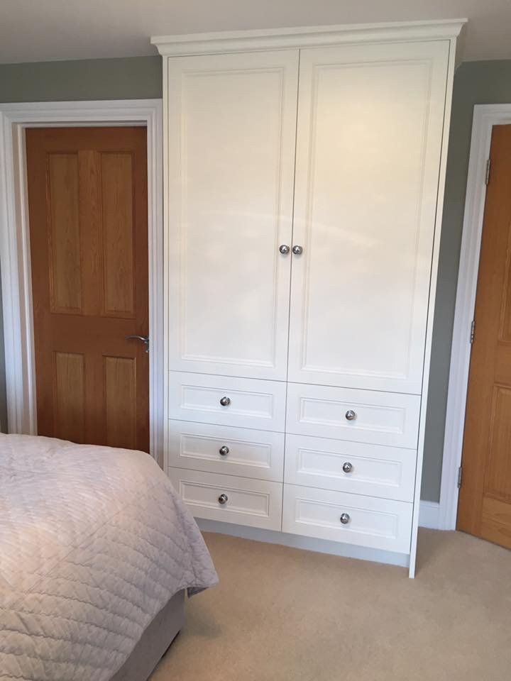 A bedroom with a bed and a wardrobe with drawers