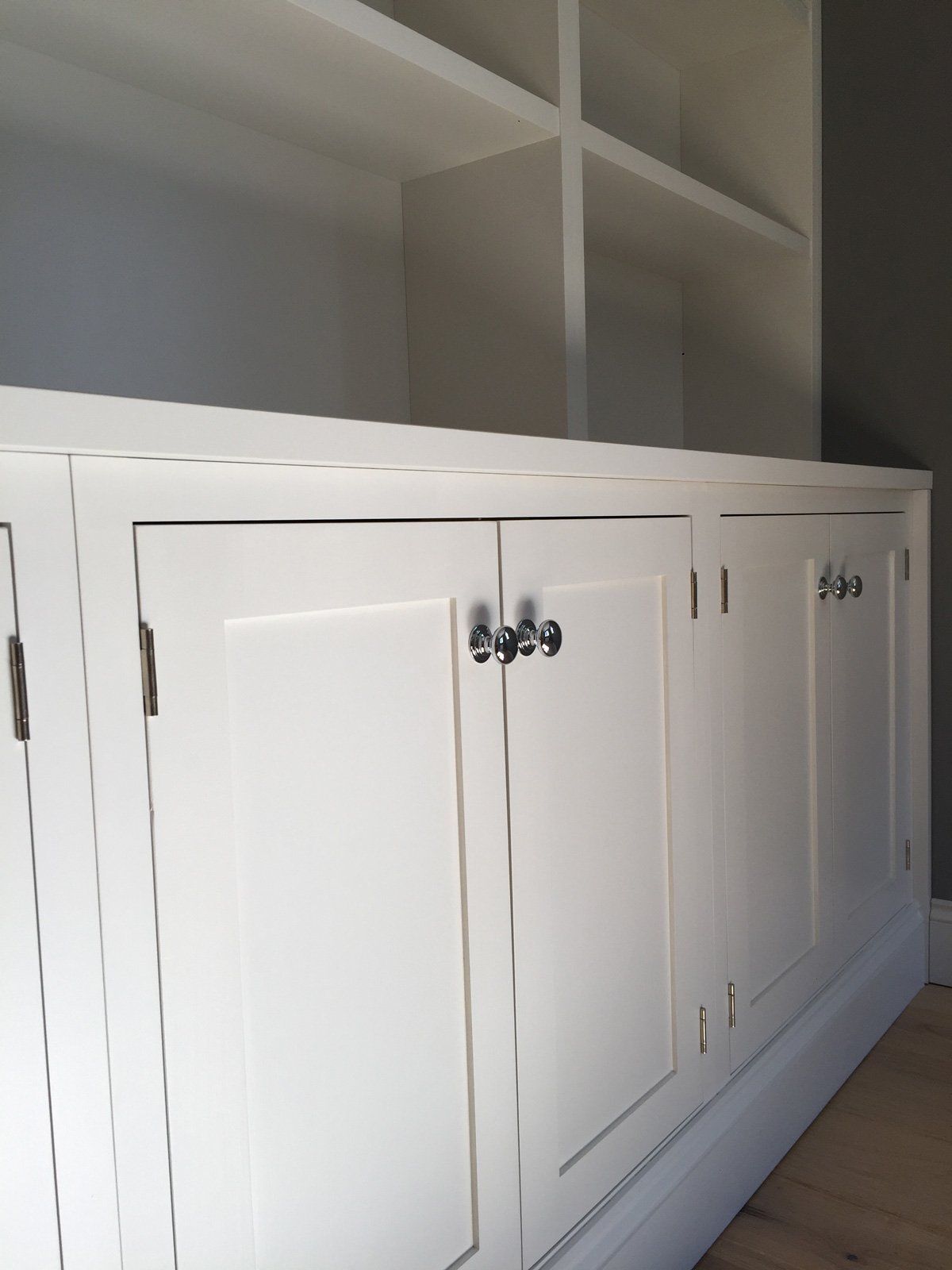 A row of white cabinets with silver handles in a room