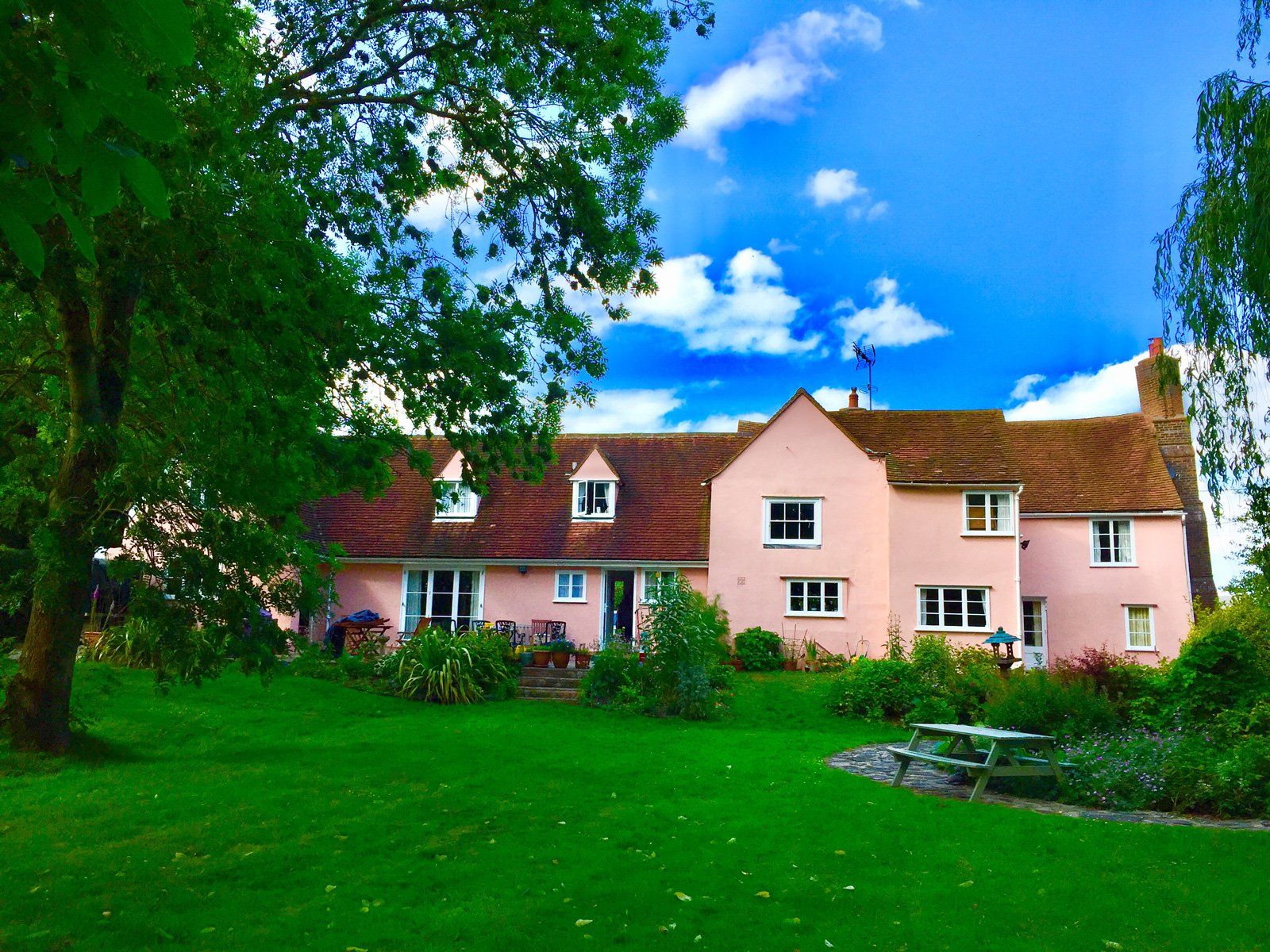 A large pink house with a picnic table in front of it