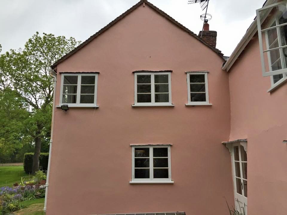 A pink house with white windows and a chimney on top