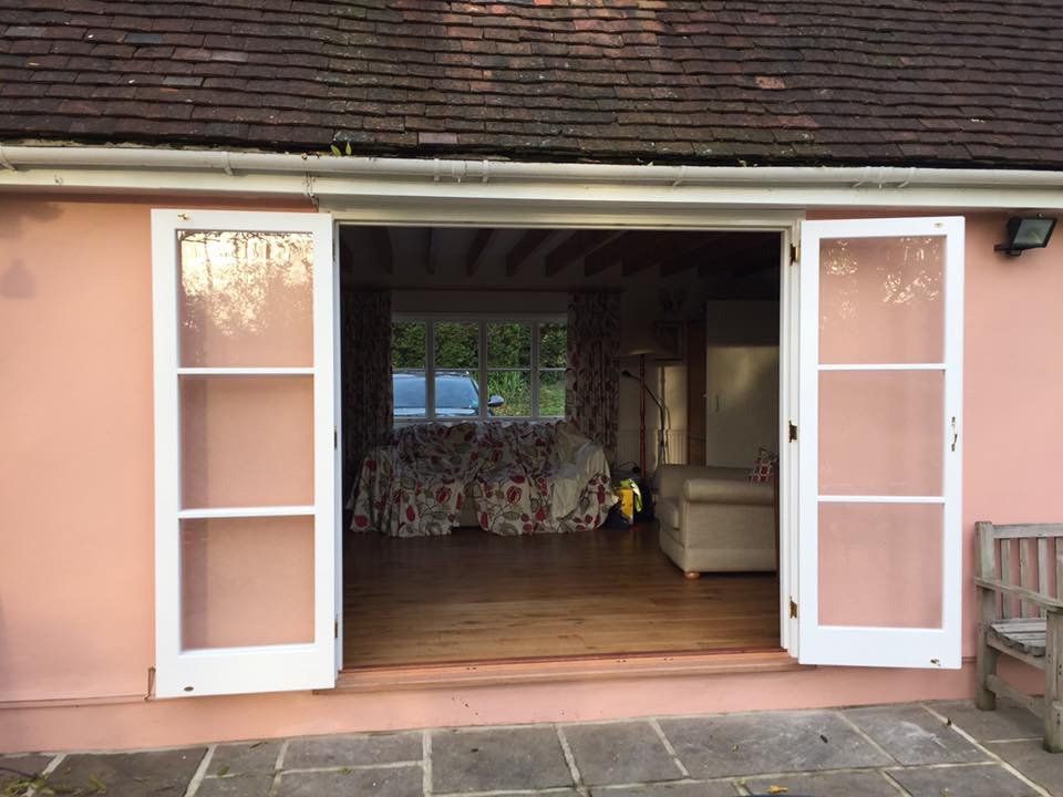 A pink house with white sliding glass doors open to a living room