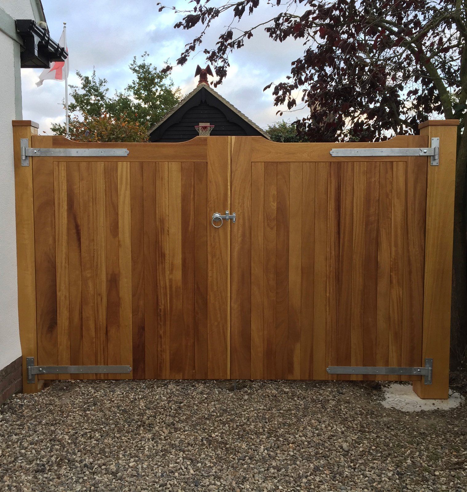 A wooden gate is sitting on gravel in front of a house