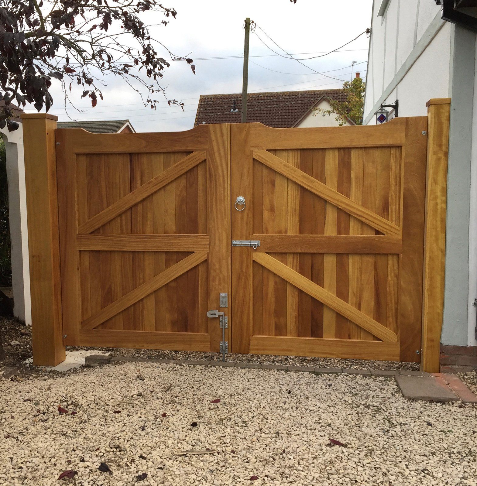 A wooden gate is sitting on gravel in front of a house