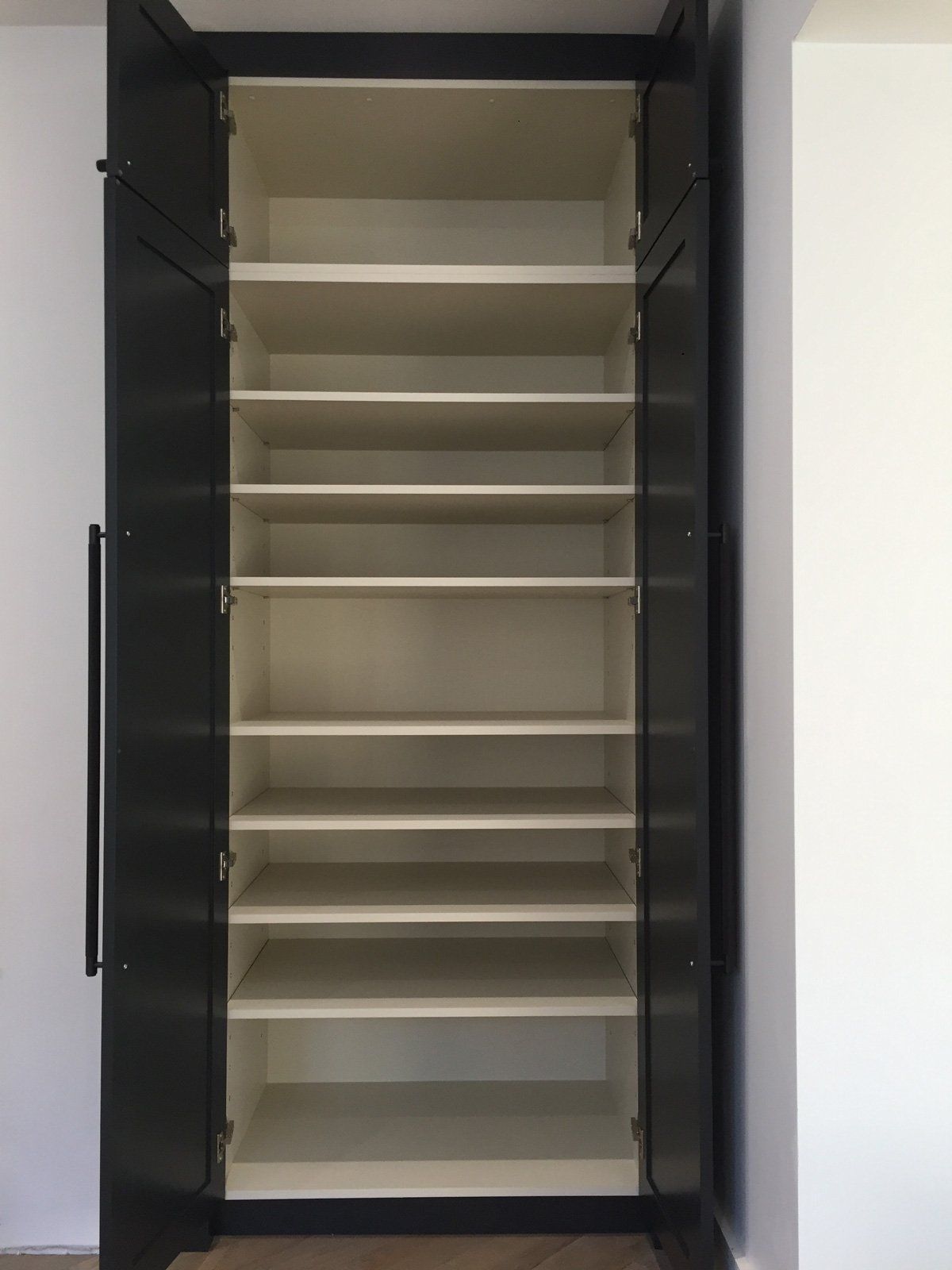 A large empty closet with lots of shelves and doors.