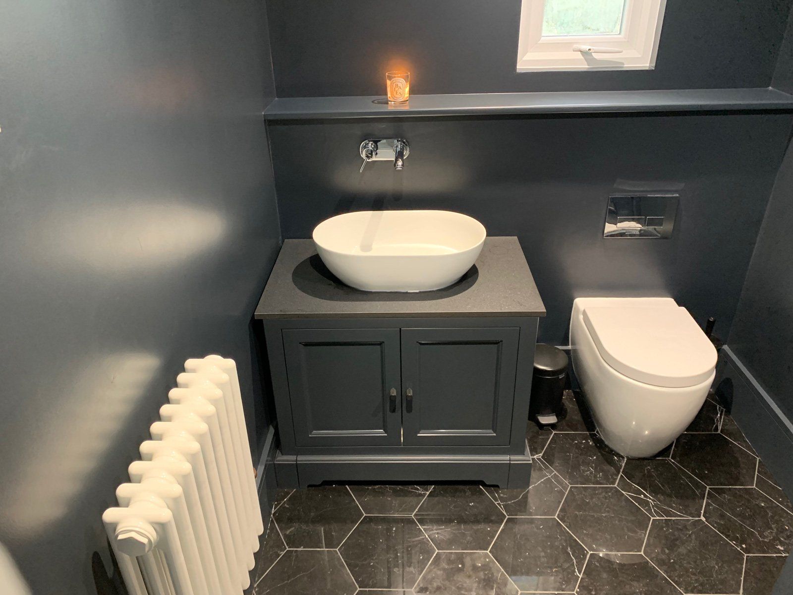 A bathroom with a sink , toilet and radiator.
