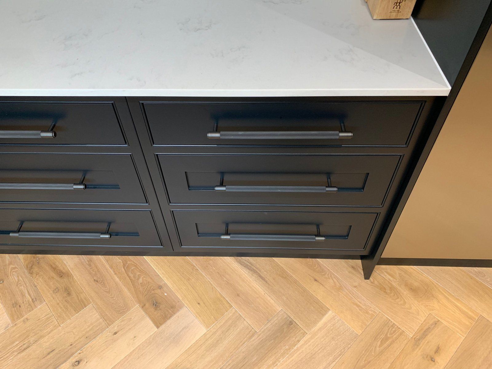 A kitchen with black drawers and a white counter top.