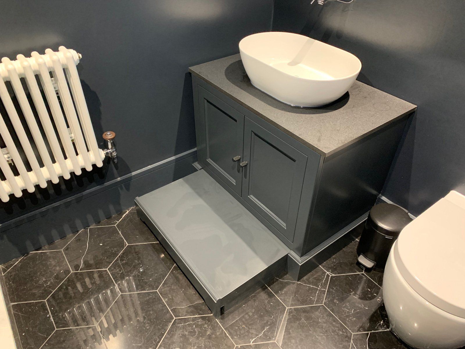 A bathroom with a sink , toilet and radiator.