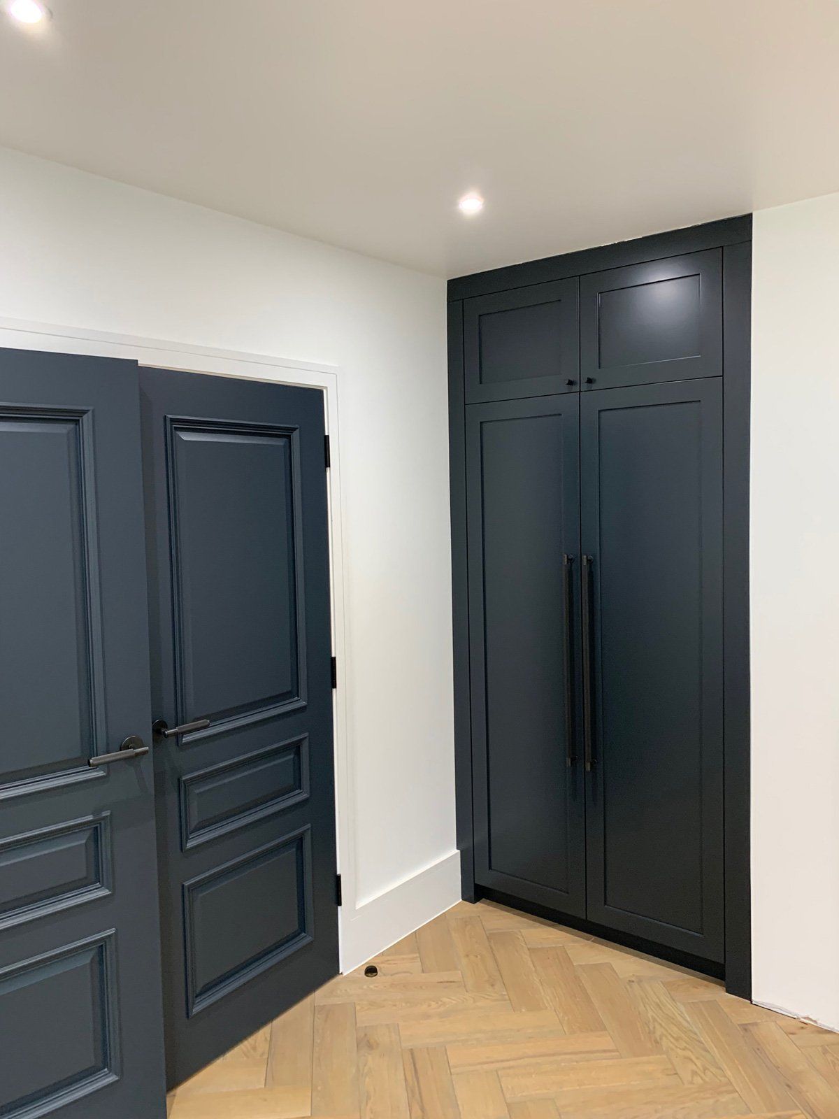 A room with two black doors and a wooden floor.
