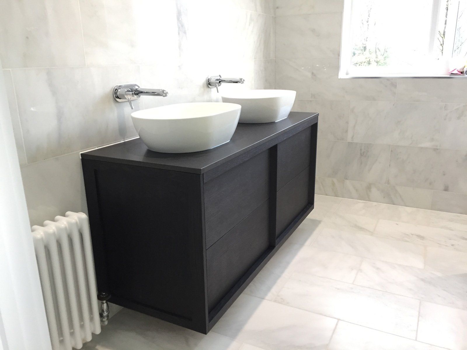 A bathroom with two sinks and a radiator