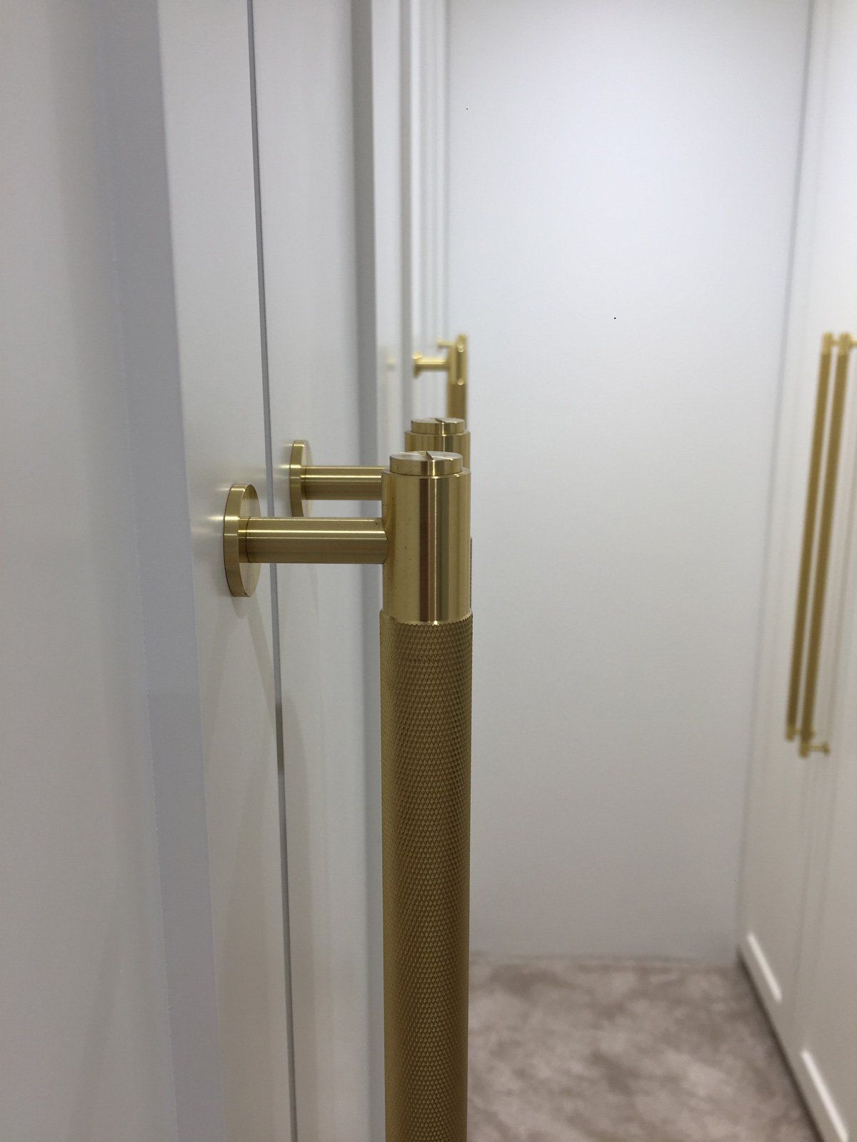 A close up of a gold door handle on a white door