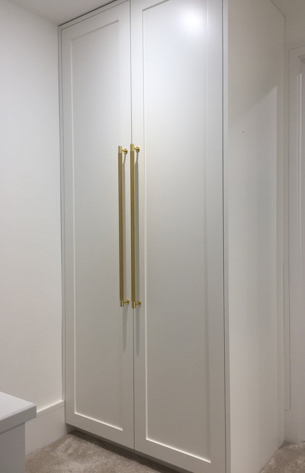 A white cabinet with gold handles in a room.