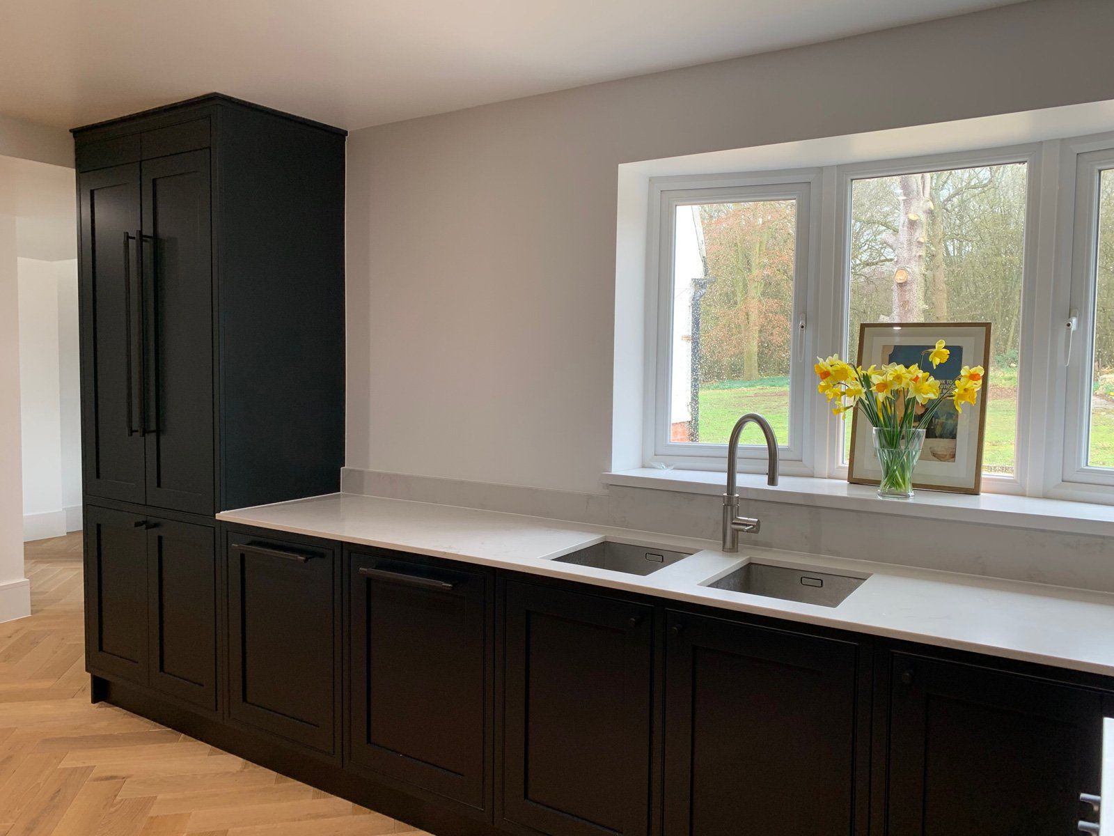 A kitchen with black cabinets , a sink , and a window.