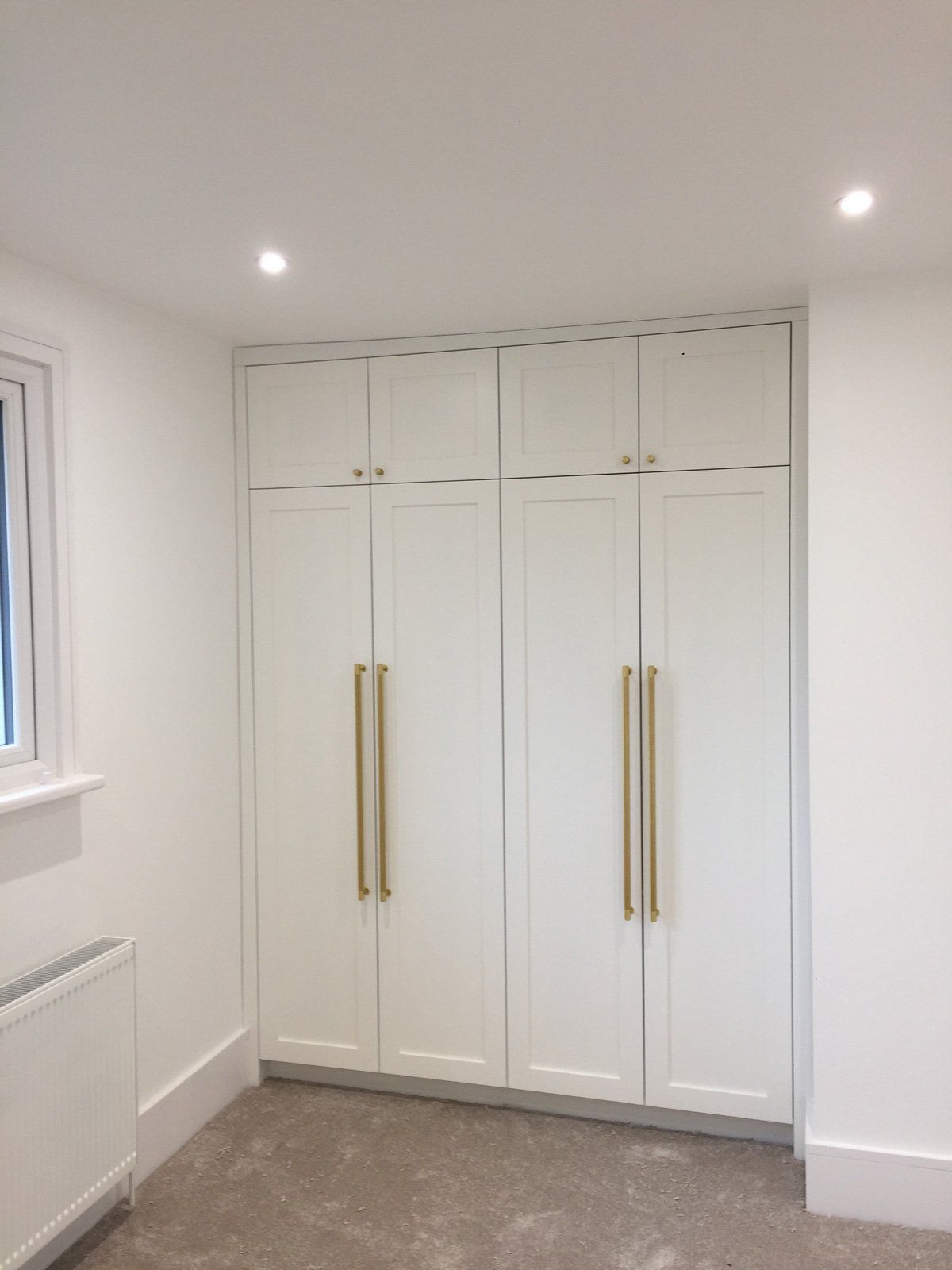 A room with a lot of white cabinets and a window.