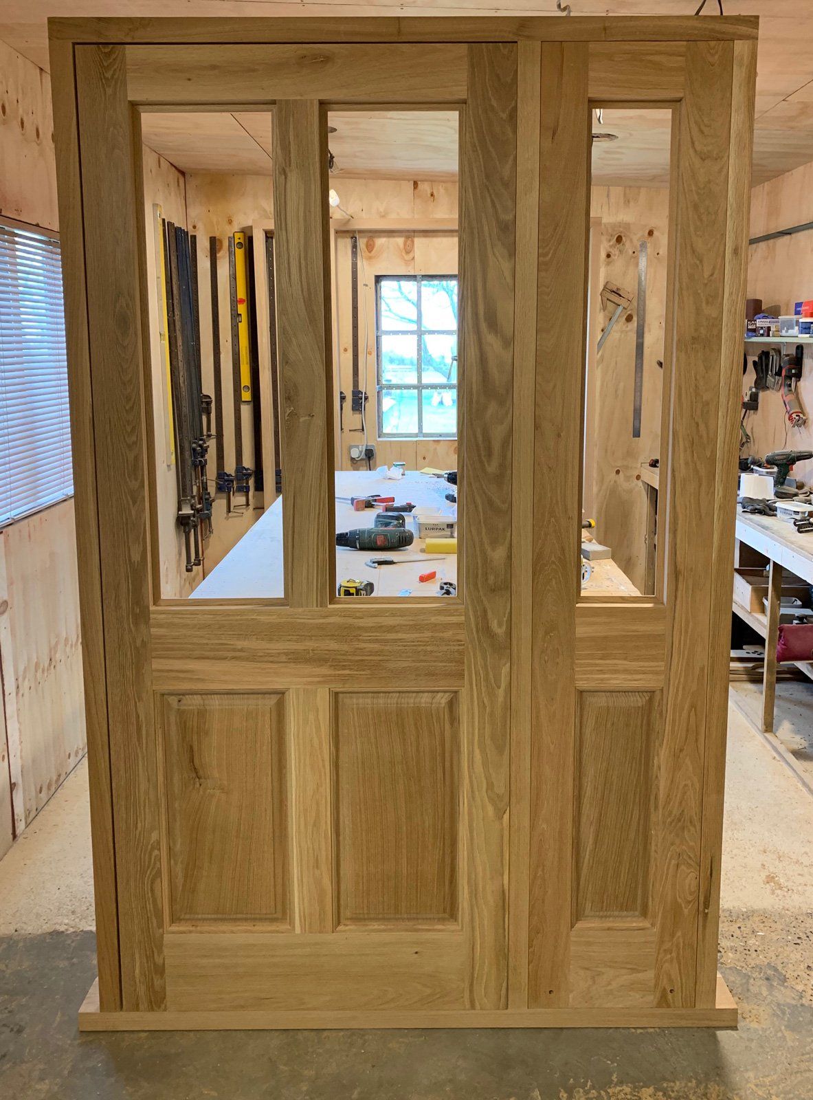 A wooden door is sitting in a room with a window.