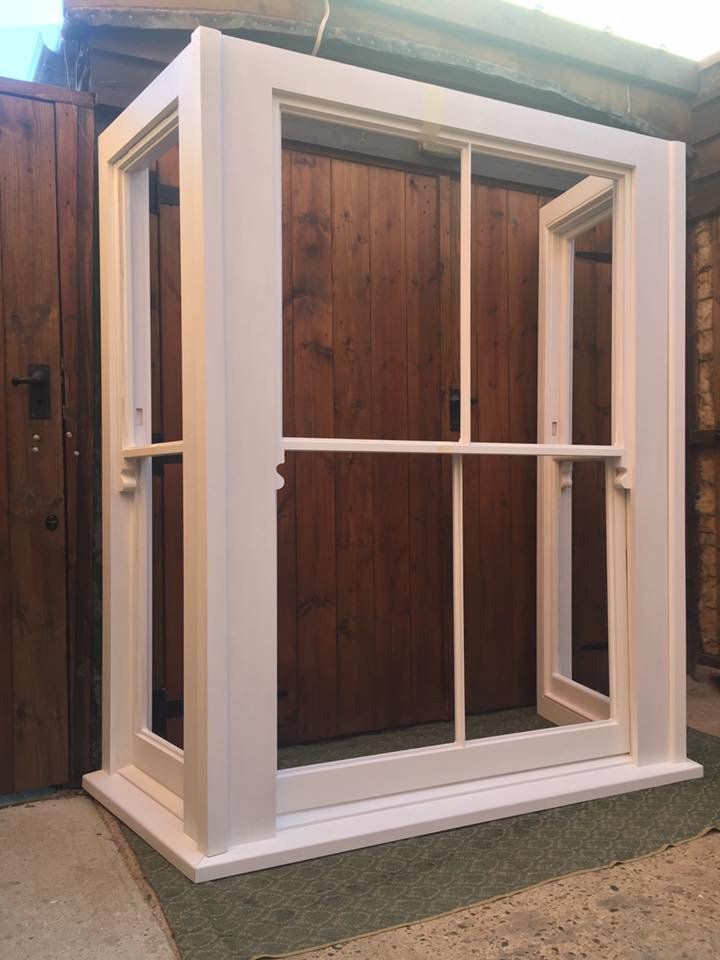 A white window frame is sitting in front of a wooden door.