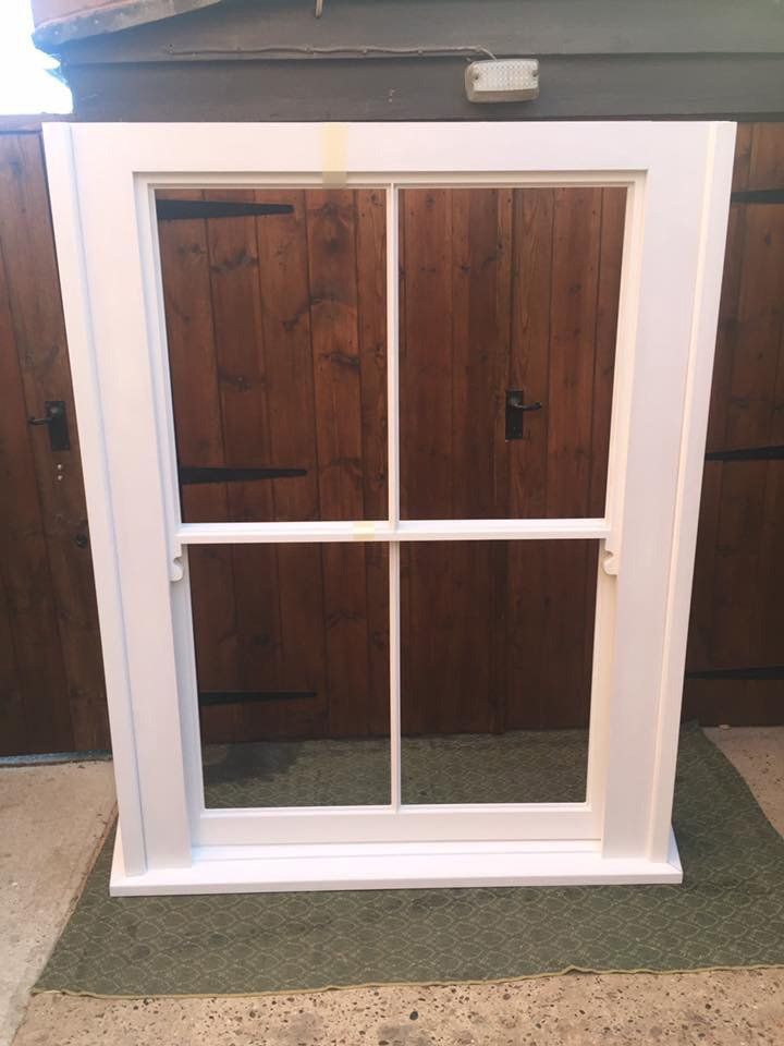 A white window is sitting in front of a wooden fence.