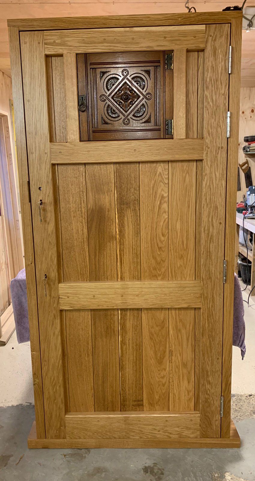 A wooden door with a glass window is sitting on the floor in a room.